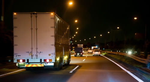 高速道路の深夜割引制度が今後変更される方針であることを伝える画像。夜間の高速道路をトラックが走行している